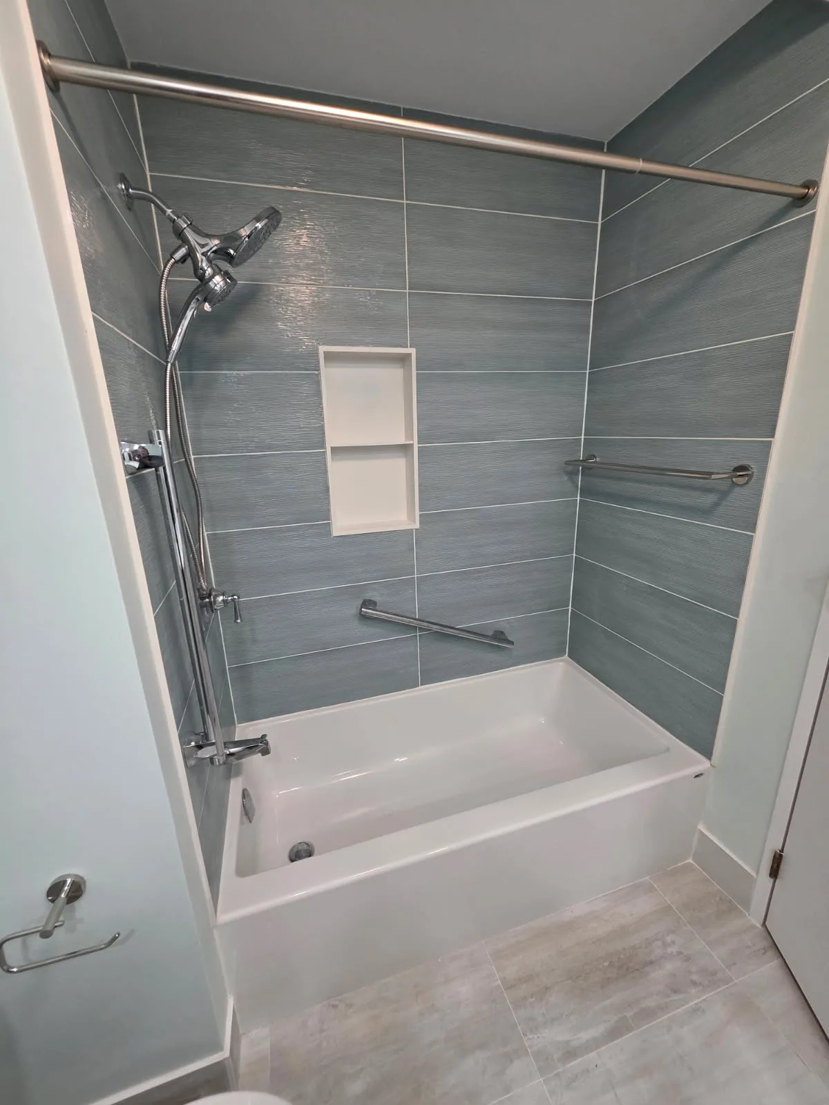 New tiled tub surround with recessed niche and modern fixtures