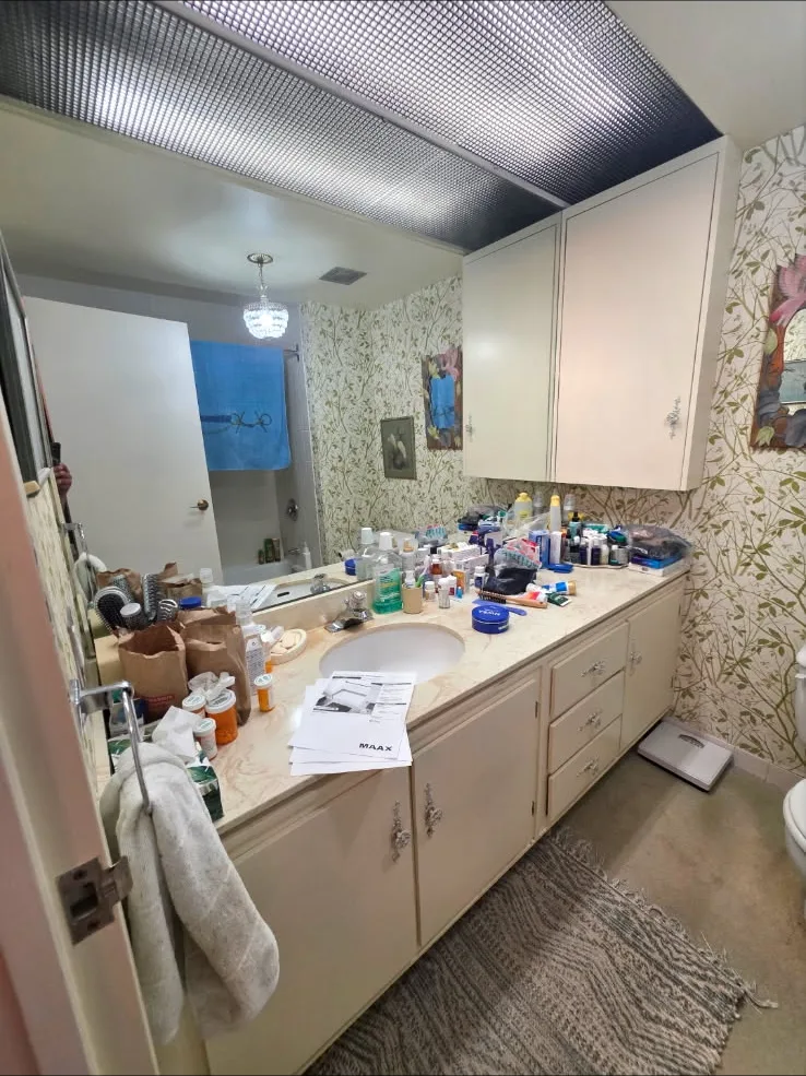 Dated bathroom vanity with floral wallpaper before renovation