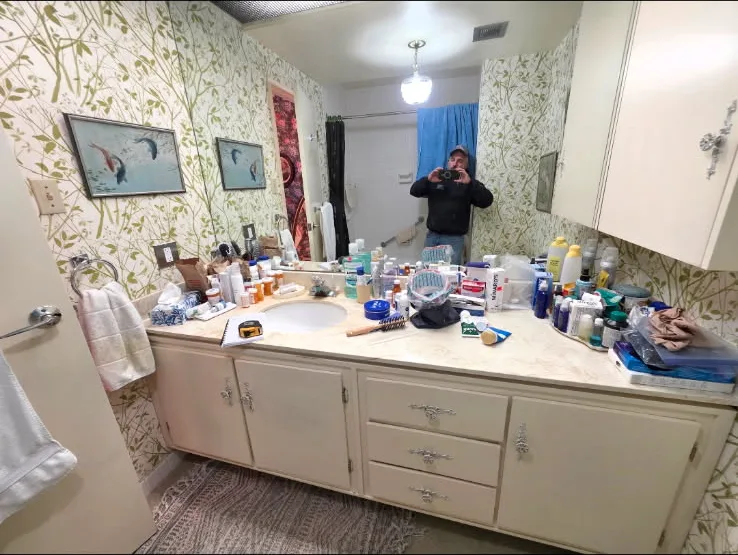 Wide view of the original bathroom vanity and wallpaper