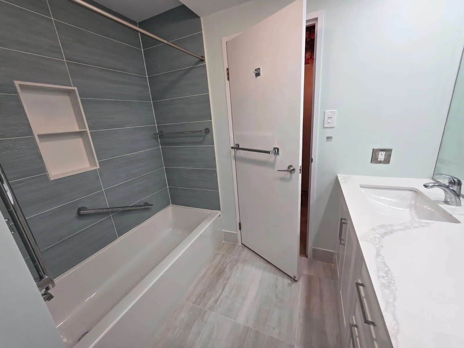 Finished bathroom with tiled tub, quartz vanity and tile flooring
